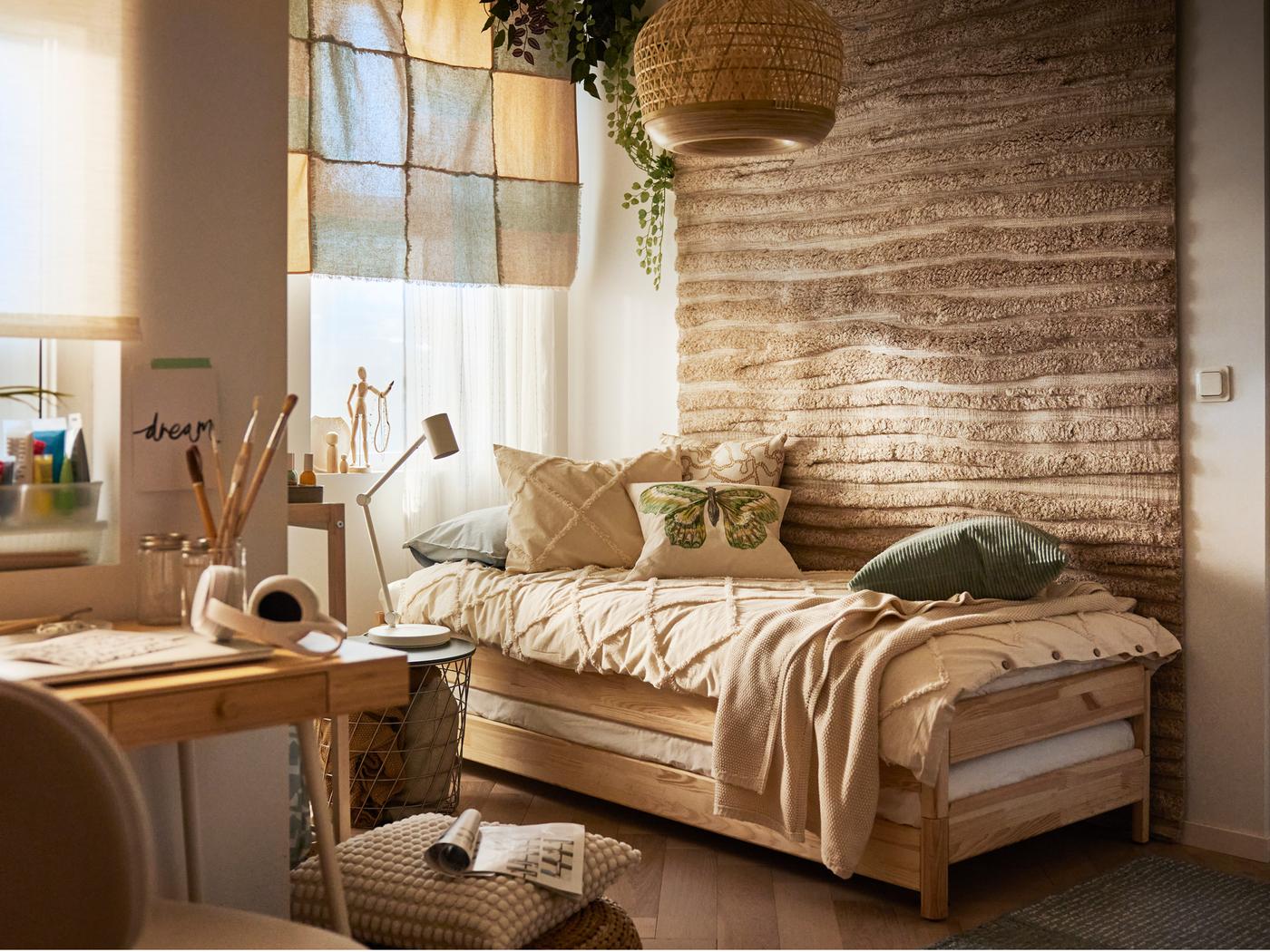 In einem Raum im rustikalen Stil steht ein stapelbares UTÅKER Bett, auf dem Bettzeug in NYPONLUGGMAL Bettwäsche liegt. An der Wand hinter dem Bett hängt ein strukturierter Teppich.