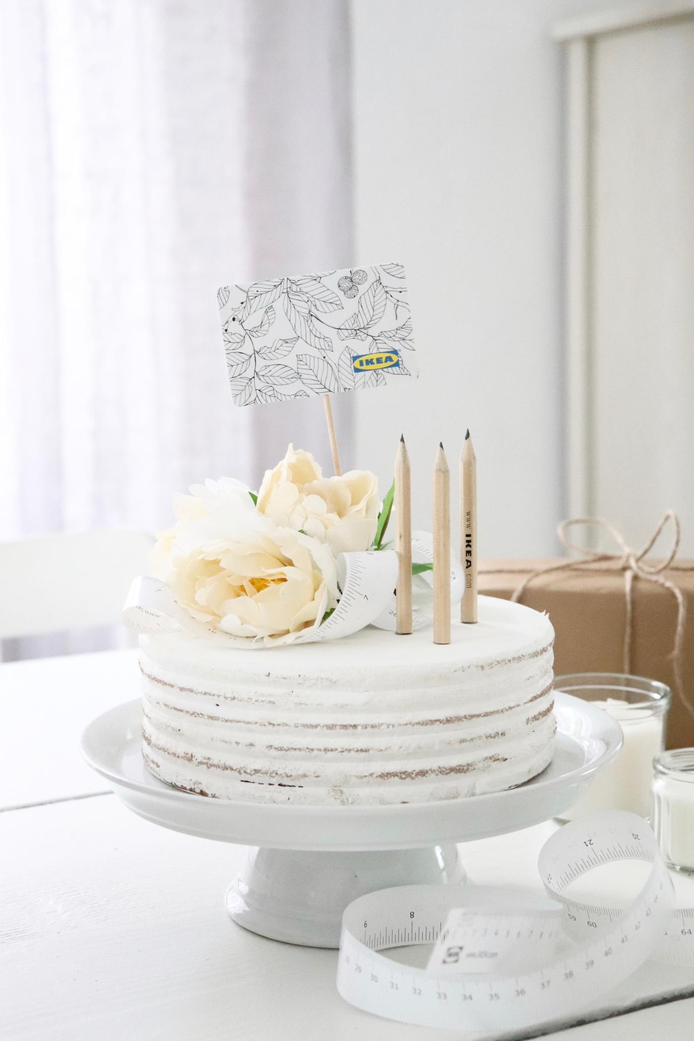 In einer weißen Torte stecken IKEA Bleistifte und eine IKEA Geschenkkarte.