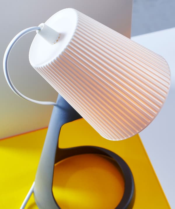 În prim-plan, un abajur alb așezat pe o lampă de birou.