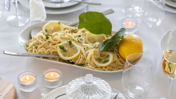 In the middle of the table is a plate of lemon pasta.