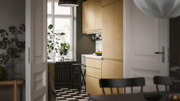 In una cucina piccola, dal design essenziale, frontali VOXTORP effetto rovere con maniglie integrate e una lampada a sospensione SKURUP nera.