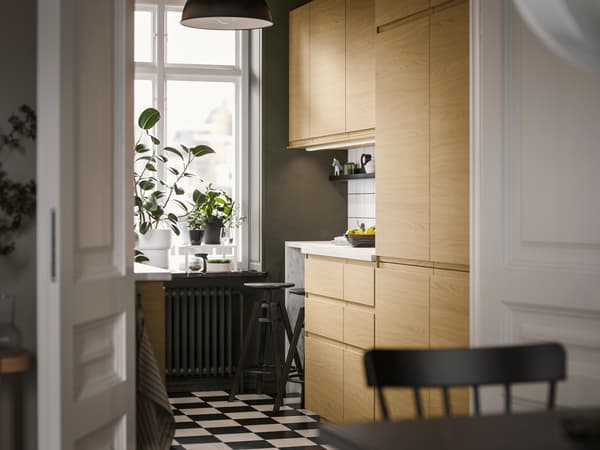 In una cucina piccola, dal design essenziale, frontali VOXTORP effetto rovere con maniglie integrate e una lampada a sospensione SKURUP nera.