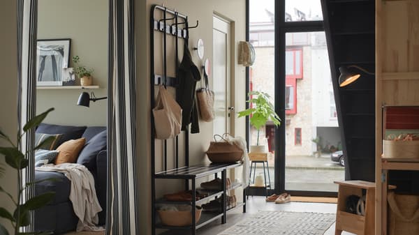 Industrial Style Garderobe: Eine helle Diele mit einem PINNIG Garderobenständer aus schwarzem Metall und einer Bank mit Schuhaufbewahrung.