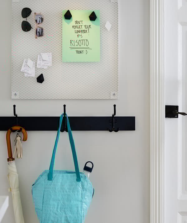 Ingresso con pannello portaoggetti e un promemoria, una fila di ganci con una borsa portavivande - IKEA