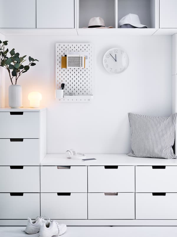 Ingresso in bianco con cassettiere NORDLI. Nella parte centrale è ricavata una panca per sedersi. Sulla parete, pannello portaoggetti SKÅDIS e decorazioni.