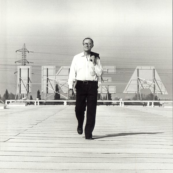 Ingvar Kamprad, founder of IKEA, on a roof in front of an IKEA logo