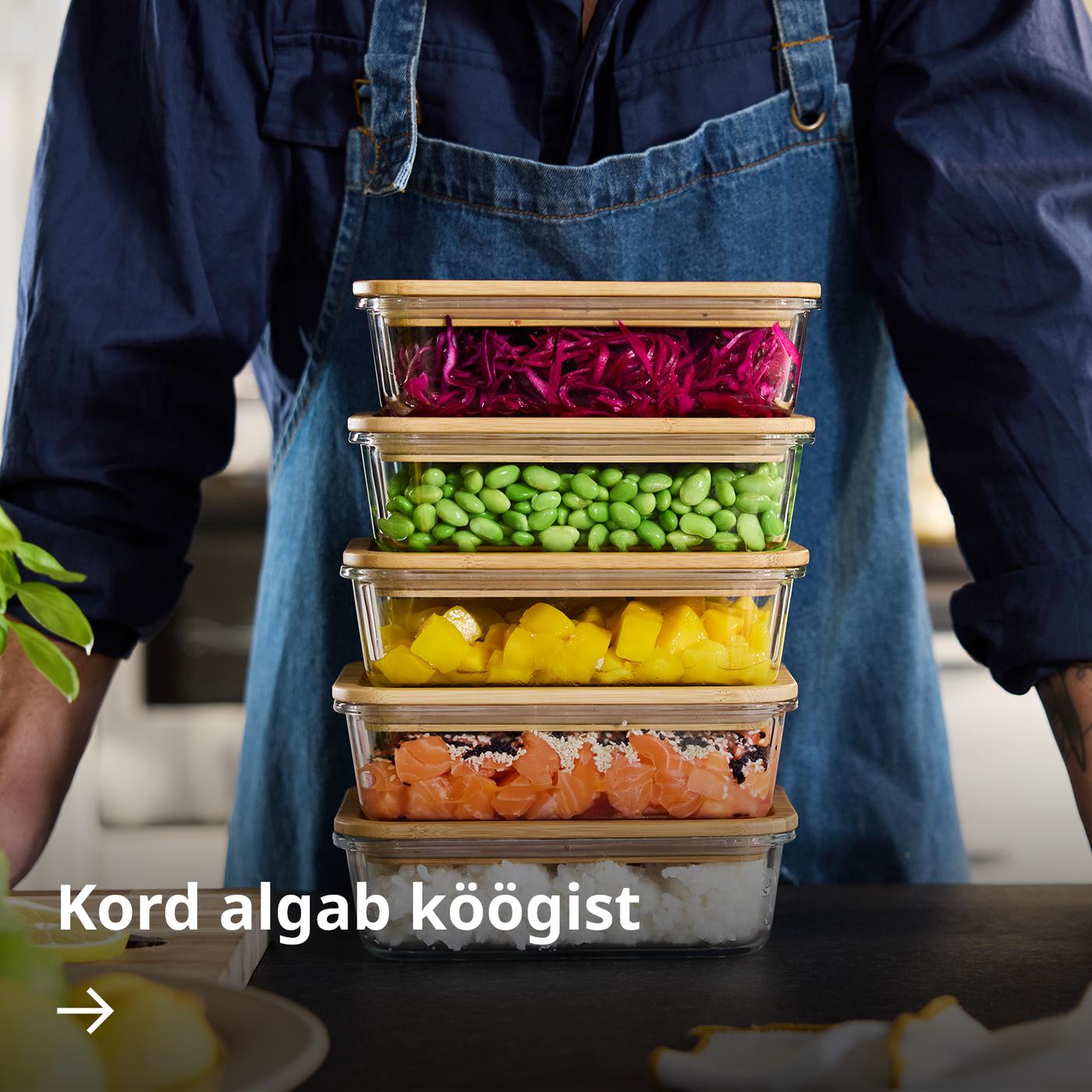 Inimene seisab virnastatud IKEA 365+ toidukarpide ees, mis on täidetud erinevate värviliste koostisosade ja toitudega.