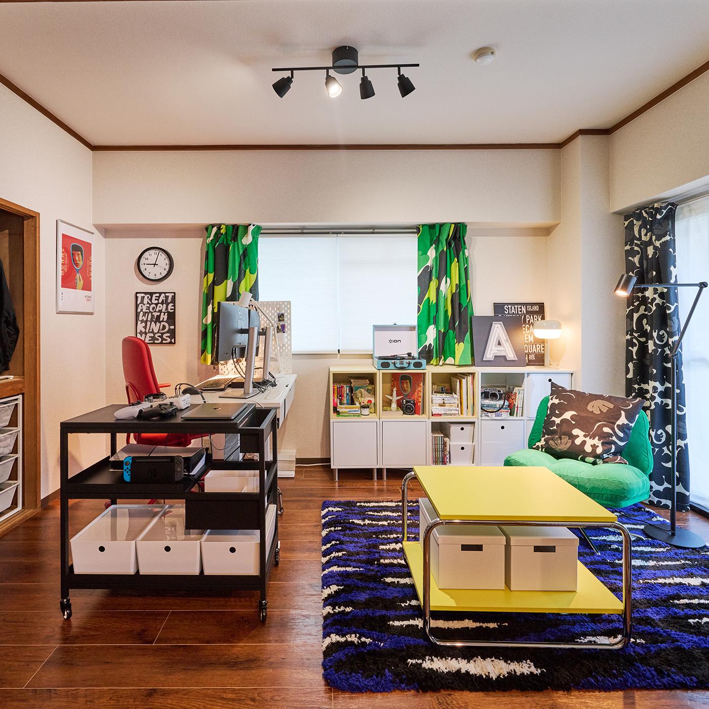 赤い椅子のあるデスクや緑のカーテン、整理された棚が並ぶカラフルなホームオフィス。