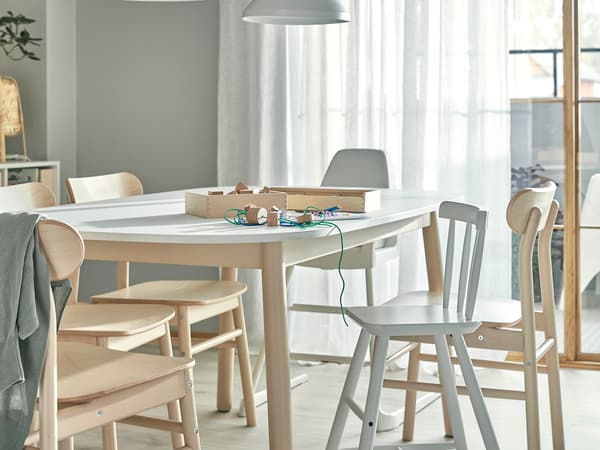 淡い木目のダイニングセットを置いた明るい食卓。グレーの壁と白いカーテンでナチュラルな雰囲気。