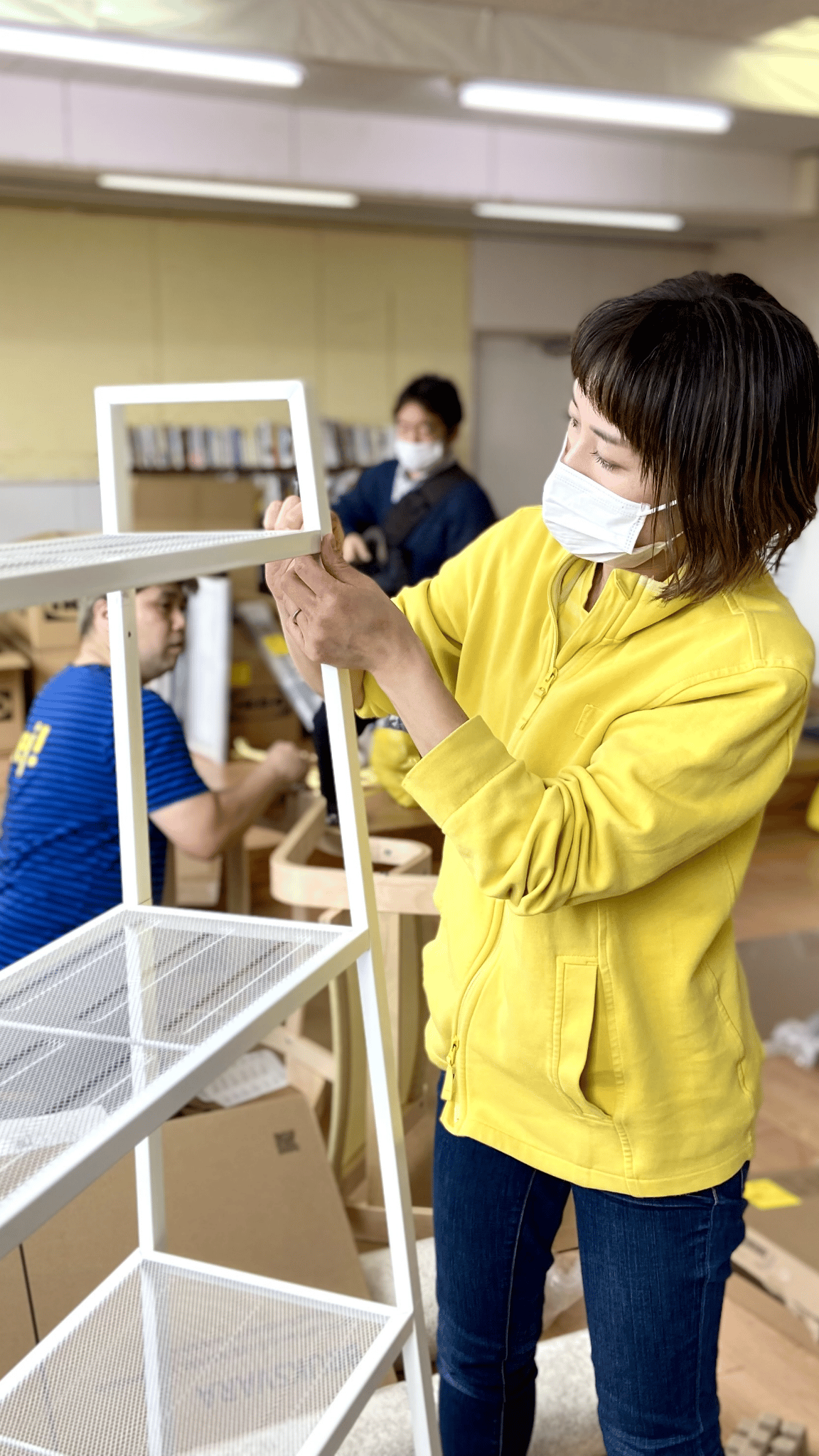 白い金属製の棚を組み立てている人