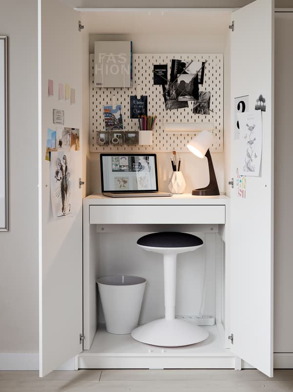 Inside a KLEPPSTAD wardrobe, a MICKE desk, a NILSERIK standing support, a lamp and a pegboard form a very compact workspace.