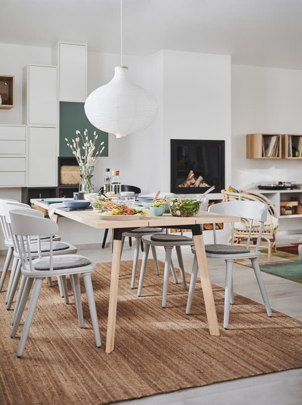 Intérieur combinant salon et salle à manger avec un foyer, un rangement mural, une table à manger YPPERLIG et des chaises OMTÄNKSAM.