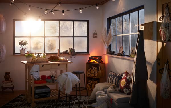 Intérieur d’un petit espace de type maisonnette. Les fenêtres suggèrent un extérieur hivernal. Buffet dressé avec de la dinde et faux feu de bois à l’intérieur.