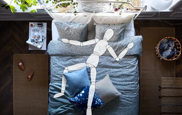 Intérieur d'une chambre à coucher avec un grand lit blanc. Une silhouette est allongée dessus.