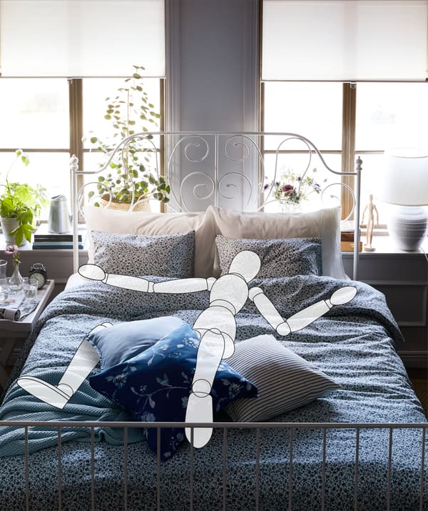 Intérieur d'une chambre à coucher avec un grand lit placé devant les fenêtres. Une silhouette est étalée sur le lit.