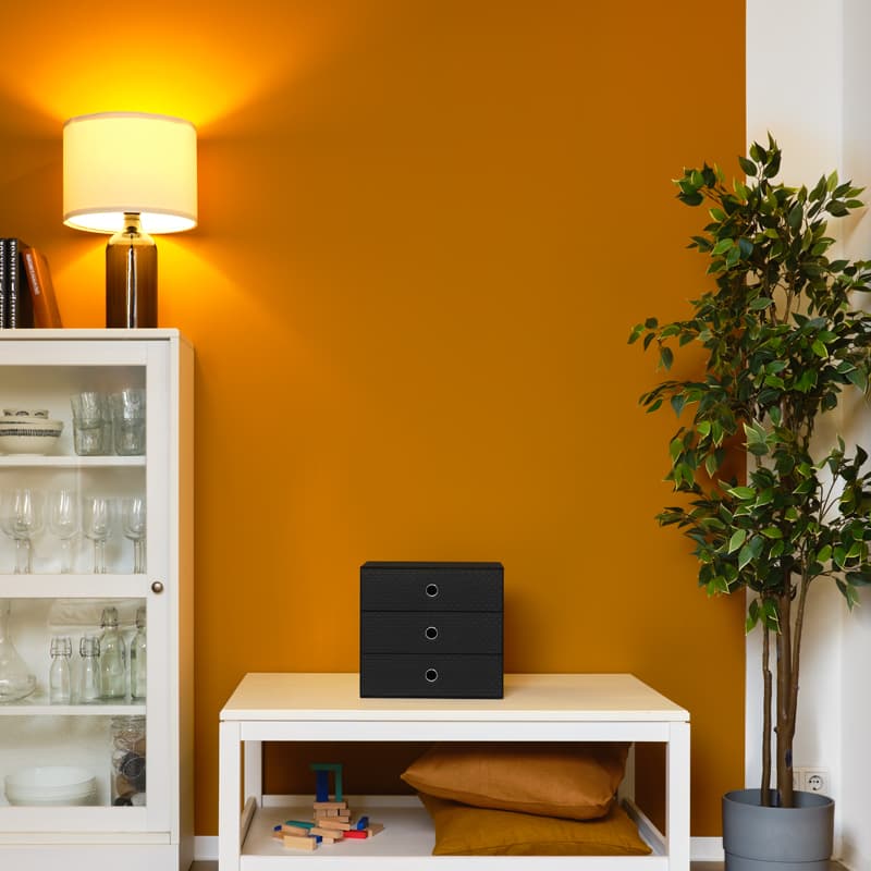 Interieurhoek met gele muur, witte meubels, een plant en sfeerverlichting