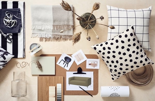 Interior design mood board with fabrics, color palette, furniture sketches and decorative accessories on a light wooden table.