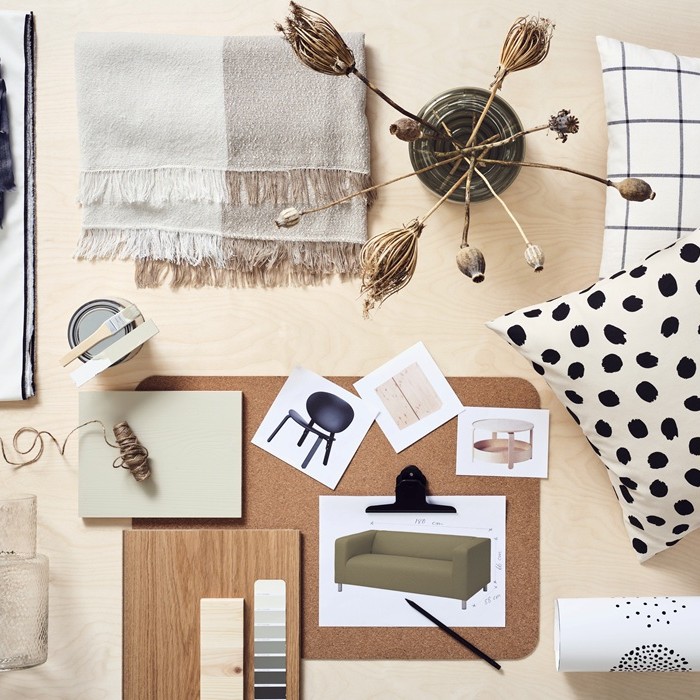 Interior design mood board with fabrics, color palette, furniture sketches and decorative accessories on a light wooden table.
