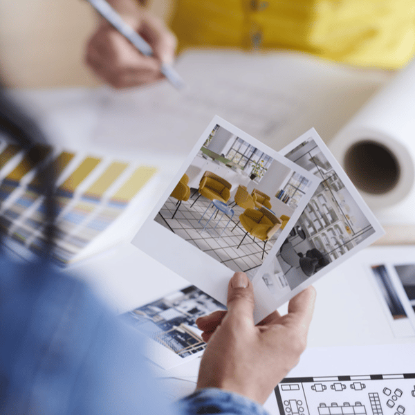 Interior designer holding photos of modern office furniture and color palette samples.