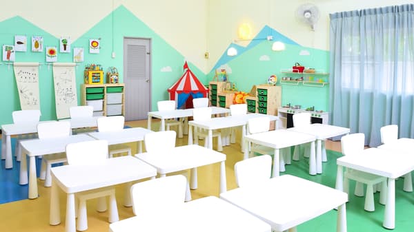 Interior of a classroom with white MAMMUT tables and chairs, DUKTIG play furniture, TROFAST storage boxes in shelves and more.