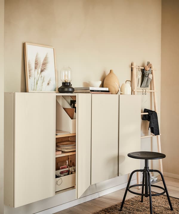 Interiorul unei camere asortate complet cu piesele de mobilier din lemn blond; panou perete, corpuri suspendate, covor și decorațiuni și un taburet negru.