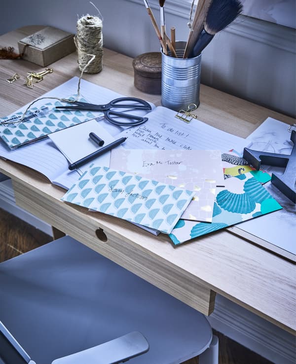 Invitacions MÅNGFALD amb sobres en una combinació d'estampats i colors, al costat d'una llista de tasques pendents sobre un escriptori.