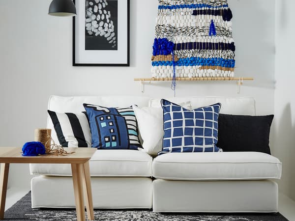白いソファにブルー系クッションを合わせた北欧風リビング。壁にアートを飾り爽やかな雰囲気。