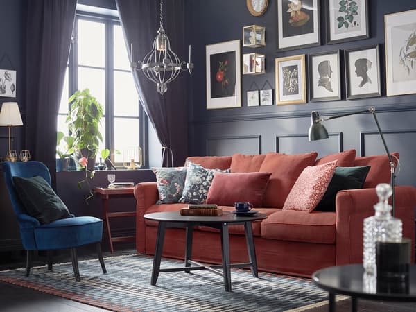 赤いソファと青いチェアを組み合わせたモダンリビング。黒い壁とアートでシックな雰囲気。