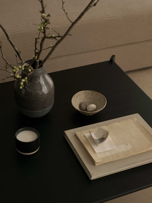 黒いテーブルの上に和紙でできた本、陶器製の花瓶や小皿、キャンドルが置いてある。