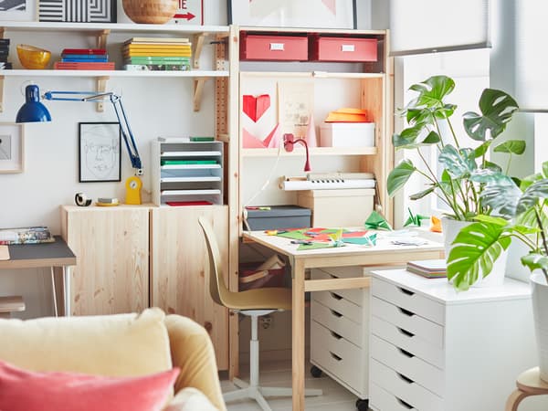 ที่ด้านหนึ่งของตู้เก็บของ IVAR/อิวาร์ ที่กว้างเท่าผนังมีพื้นที่ทำงานซึ่งทำขึ้นจากโต๊ะที่กางออก บนโต๊ะมีกระดาษสีวางอยู่