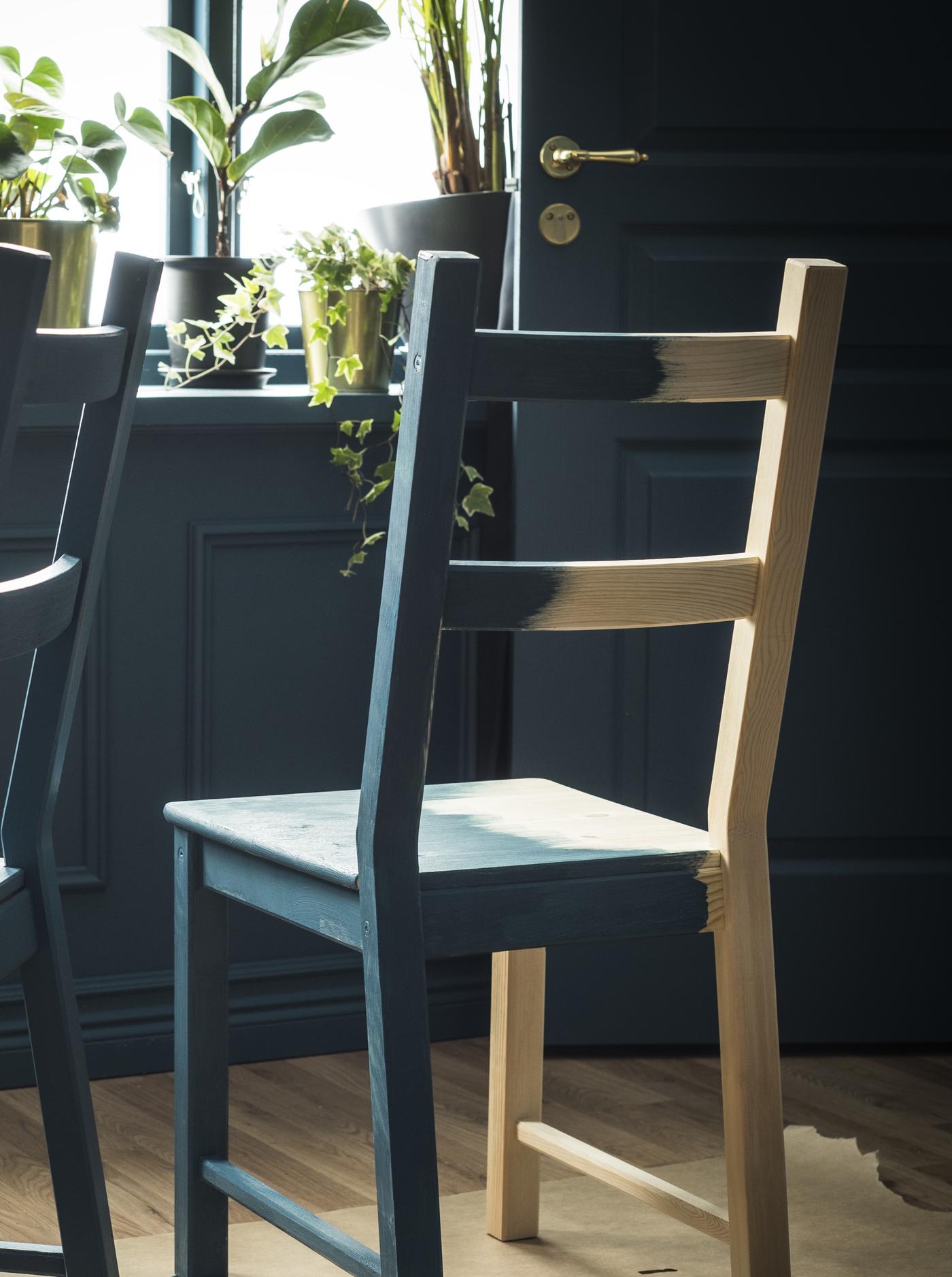 IVAR chair painted light green standing on old news papers in an empty room with light wooden floor and light pink walls.