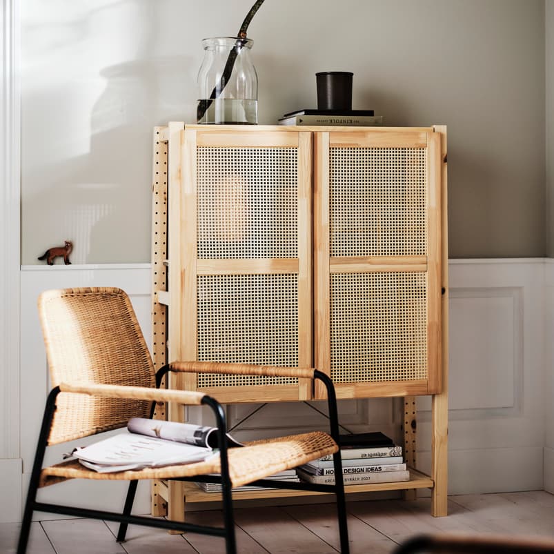 IVAR shelving unit with doors in a hallway entrance with an armchair in front and items at the bottom