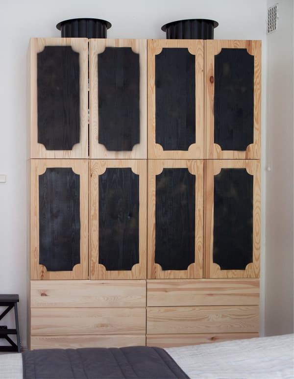 IVAR uesd as an armoire made of two 3-drawer chests below four cabinets with their doors spray-painted black.