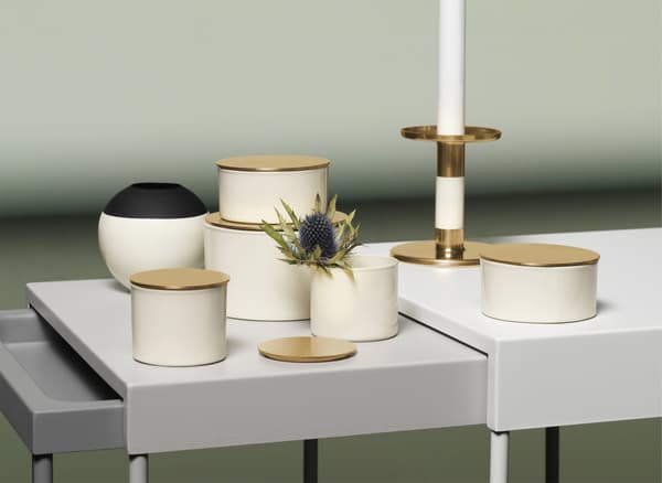 Ivory, black and gold-coloured boxes, vases and candlestick displayed on a nest of tables.