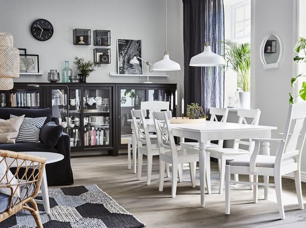 Jadalnia z białym stołem rozkładanym INGATORP i czarnymi witrynami HEMNES do przechowywania zastawy stołowej.