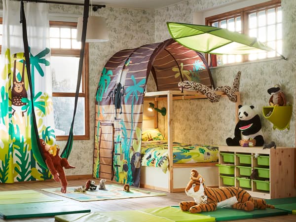 ジャングル柄の布を使ったプレイエリア付き子ども部屋。緑の収納とぬいぐるみで楽しい空間。