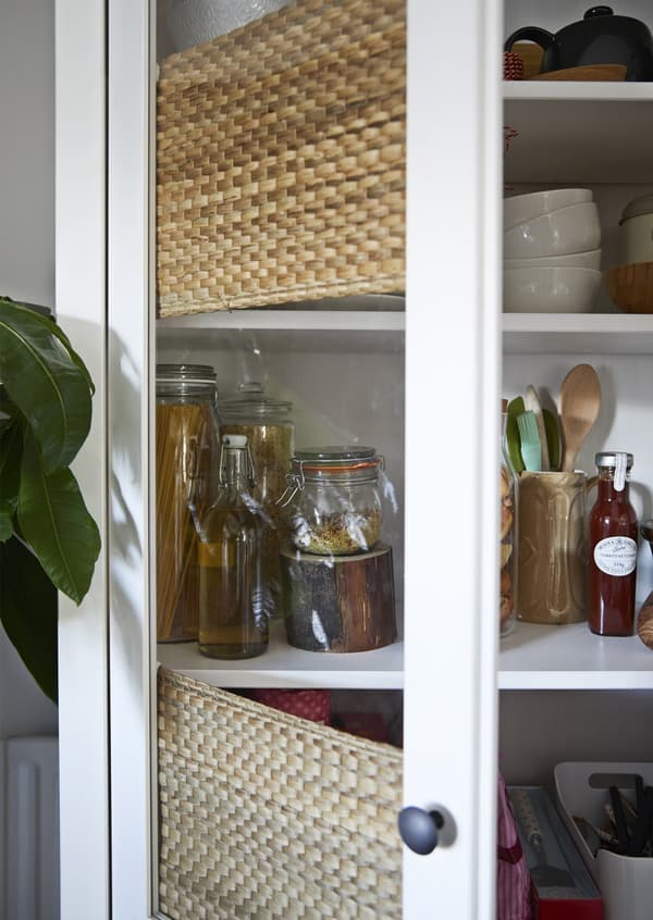 Jars and utensils stored in a glass doored HEMNES white cabinet.
