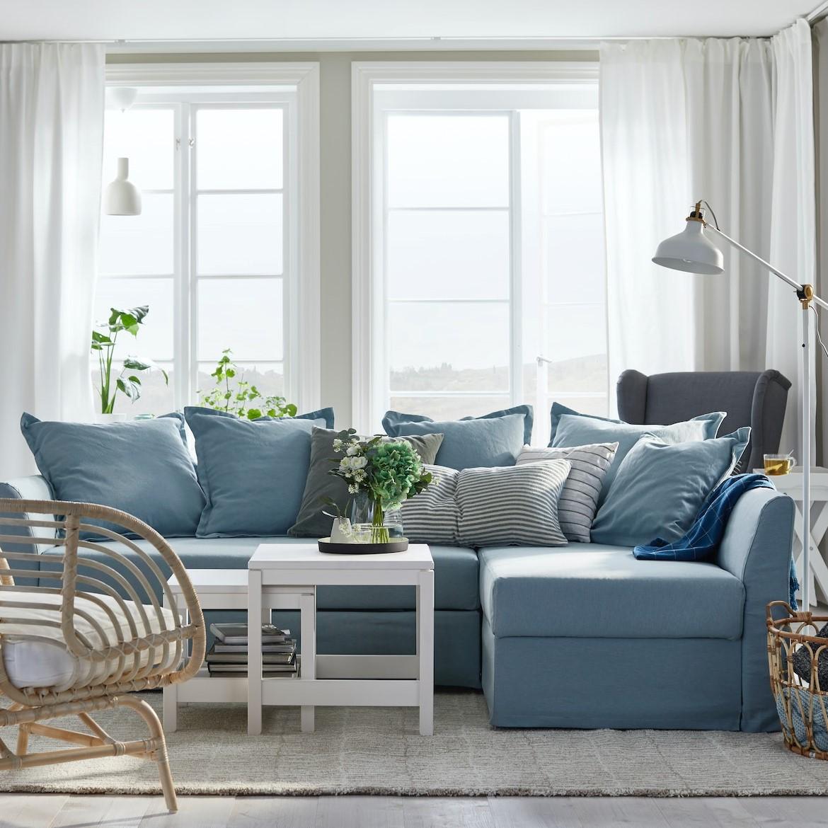 Jasny pokój dzienny z błękitna sofą, białym stolikiem kawowym i bambusowym fotelem.