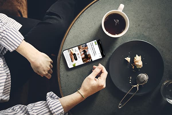 Jatetxe batean, esku bat IKEA aplikazioa erakusten duen telefono bati eusten