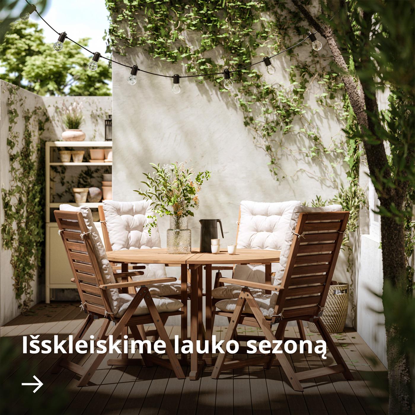 Jaukiame kiemelyje stovi apvalus lauko stalas NÄMMARÖ iš akacijos medienos ir keturios atlošiamosios kėdės su pagalvėlėmis.