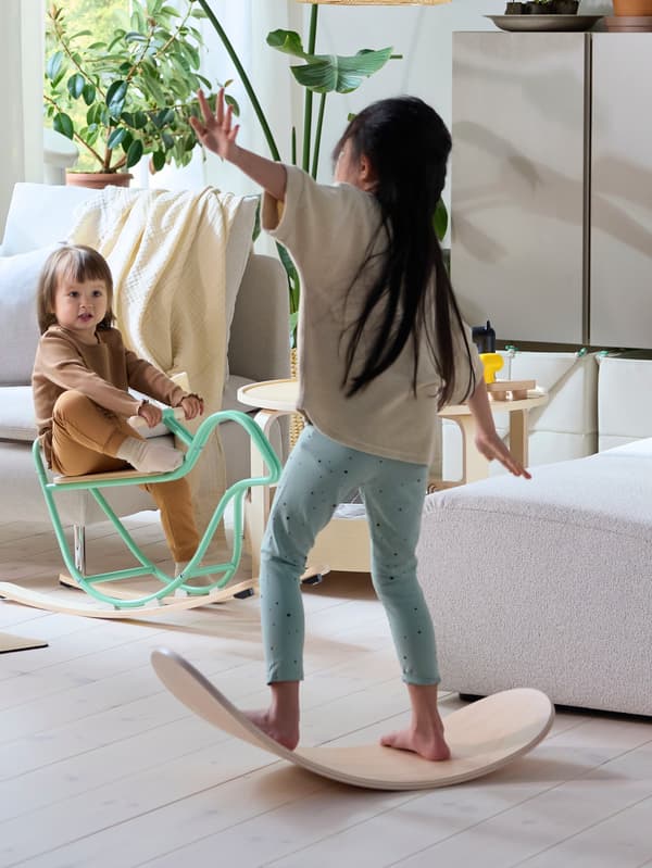 Jedno dievčatko udržiava rovnováhu na balančnej doske GREJSIMOJS, druhé sa hojdá na hojdacom vtáčikovi GREJSIMOJS.