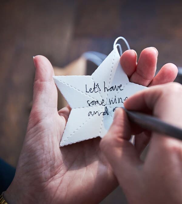 Jemand schreibt Weihnachtswünsche auf einen Papierstern