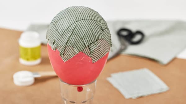 Jetzt klebt sie Textilstücke auf den Luftballon und lässt es trocknen.