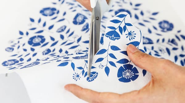 Jetzt schneidet sie von einer Serviette mit blauen Blumen einzelne Blumen aus.