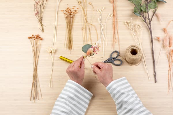 Jetzt wickeln die Hände Naturkordel um den Draht.