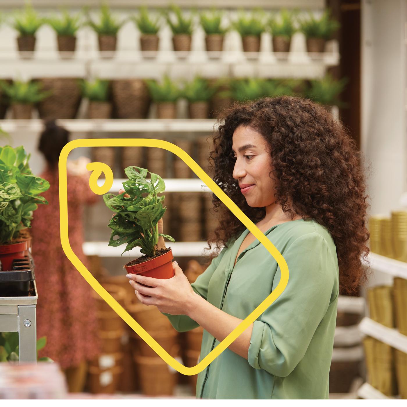 Jeune femme admirant une plante verte dans un magasin IKEA