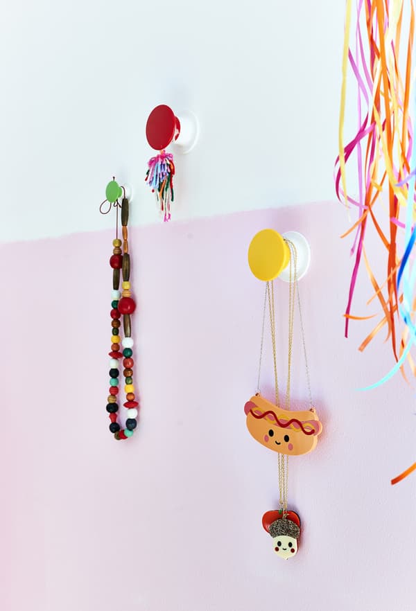 Jewellery on colourful wall hooks.