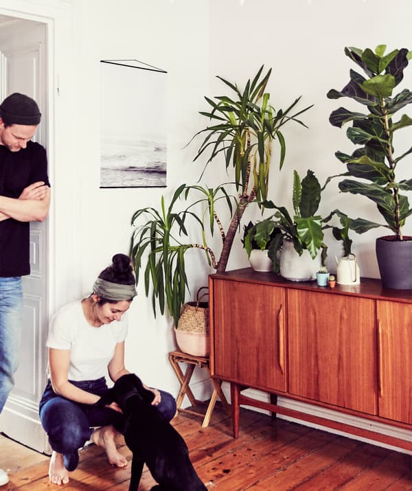 Julia e André con il loro cane accanto a una credenza anni 50 e ad alcune piante in vaso.