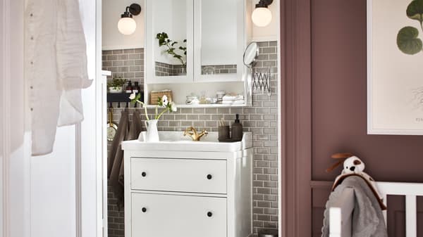 Kabinet cermin HEMNES berwarna putih, lampu dinding FRIHULT berwarna hitam dan kabinet sink HEMNES/RÄTTVIKEN dengan dua laci berwarna putih.