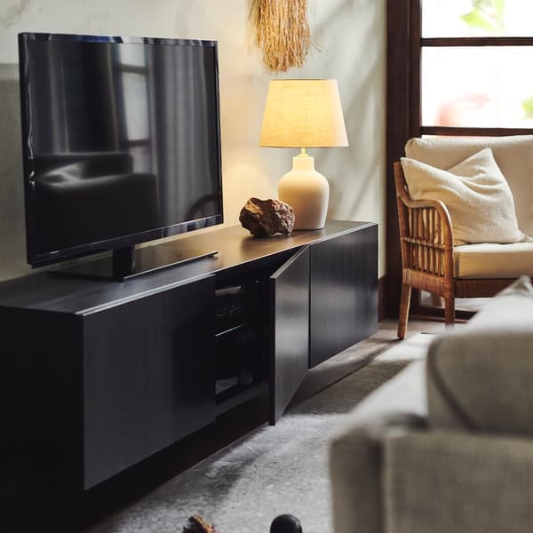 Kabinet konsol TV BESTA di ruang tamu dengan lampu meja, kerusi berlengan dan set sofa dengan ambal di atas lantai. 
